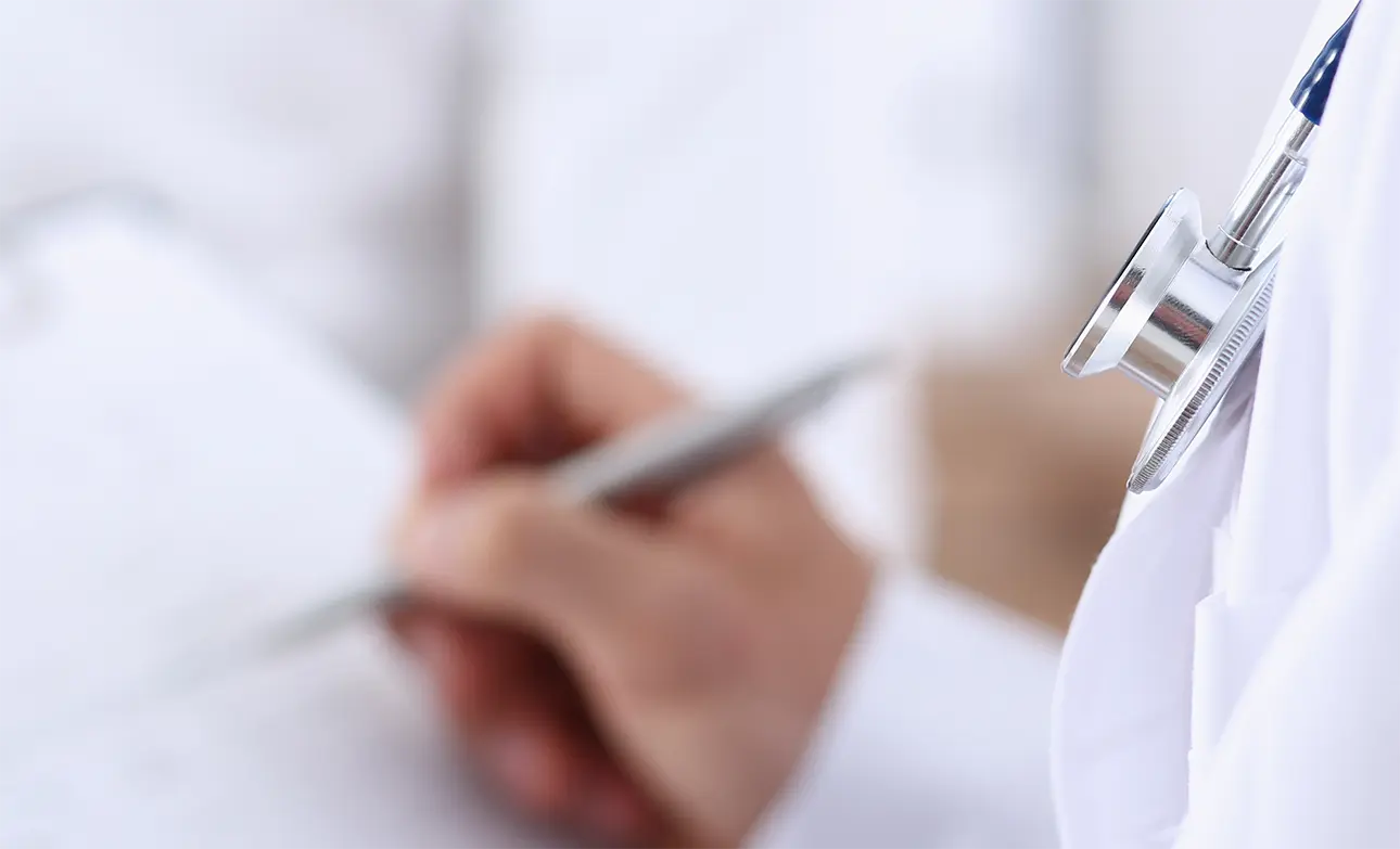 白衣を着た医師が問診票を記入している手元